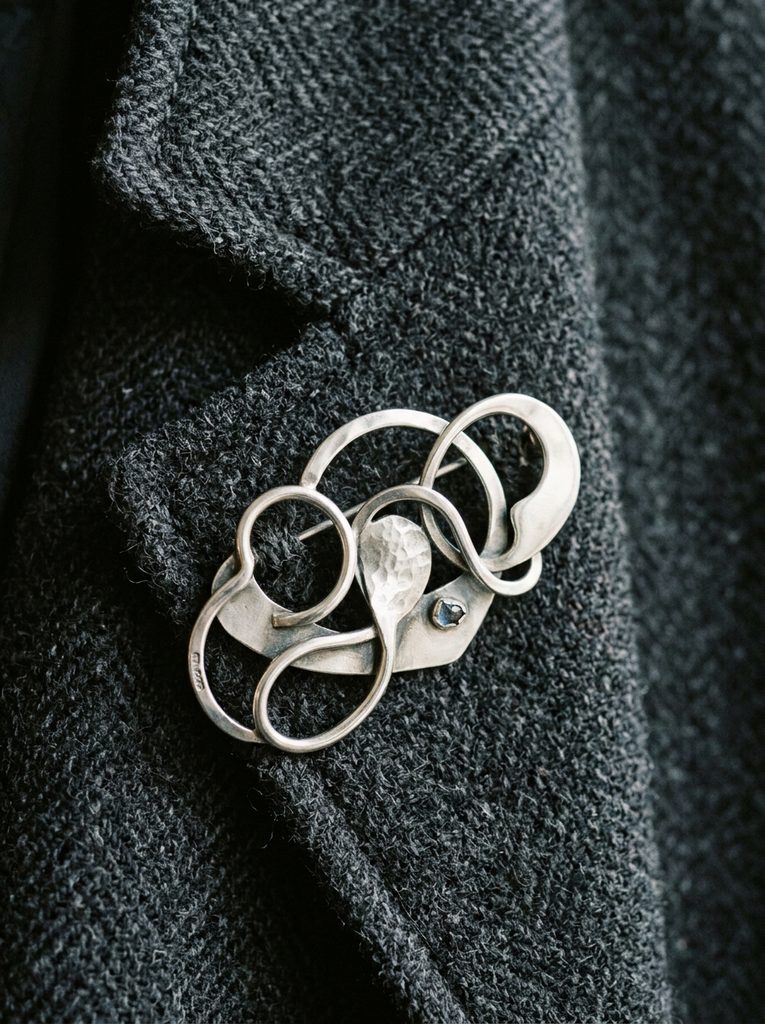 Wide sculptural sterling silver cuff worn over the ribbed sleeve of a charcoal knit sweater